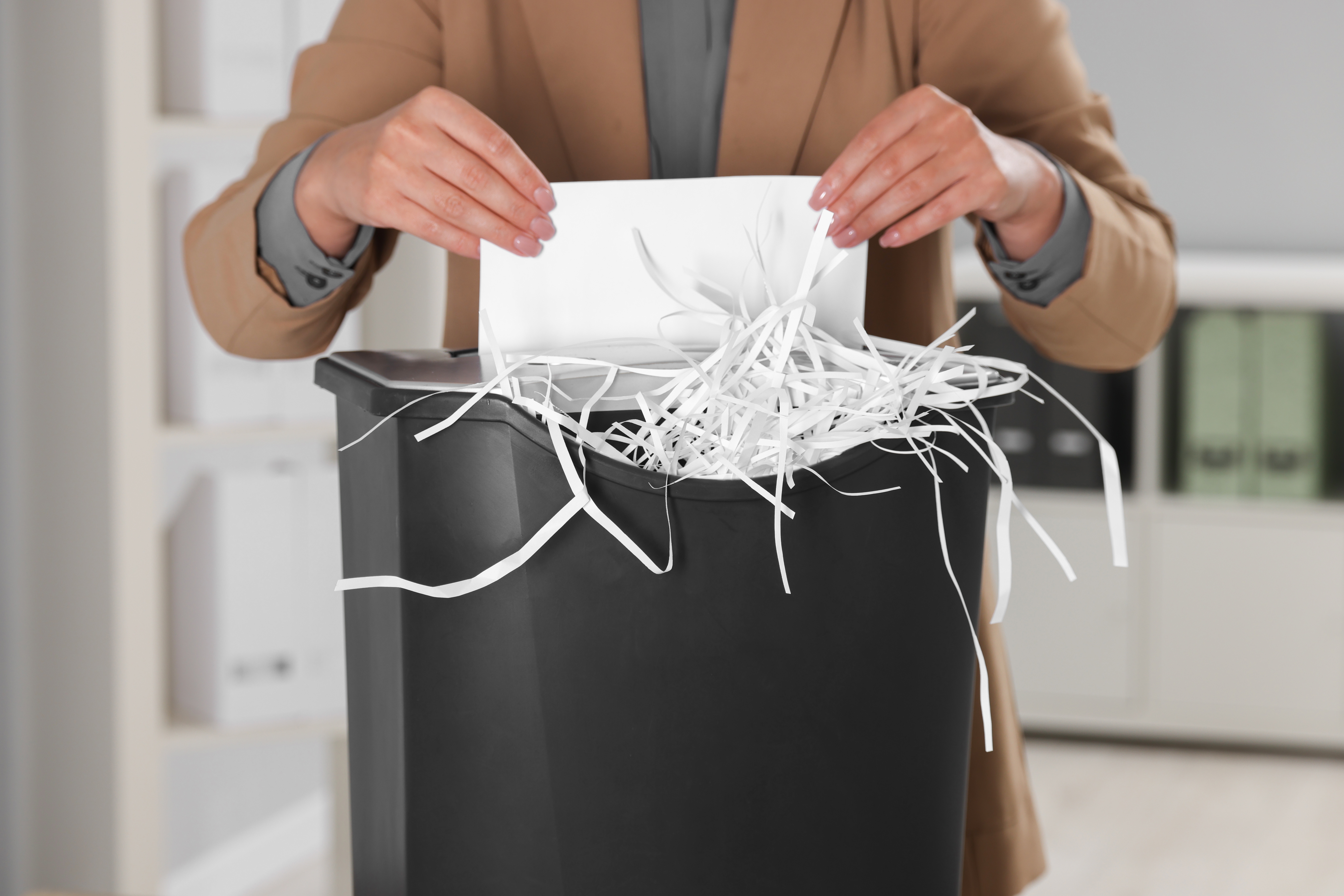 Person feeding a document into an office paper shredder.
