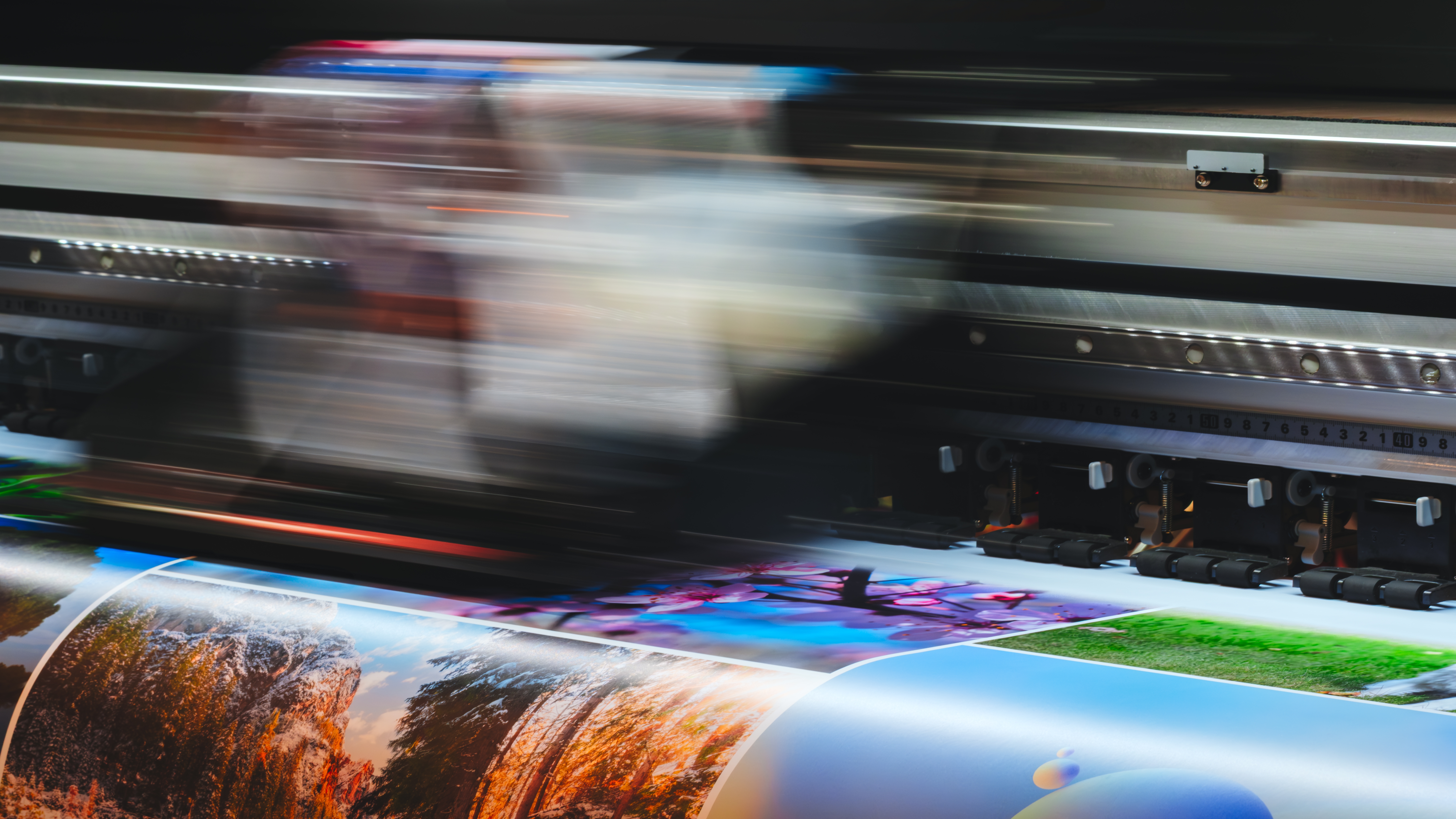 Wide-format printer in motion printing colorful landscape images.