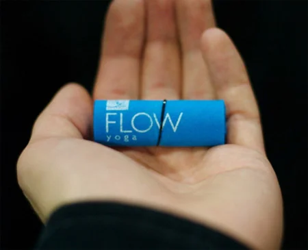 Blue cylindrical rolled business card for Flow Yoga held in an open palm.