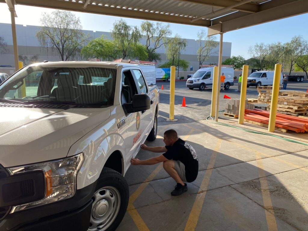 Pueblo Vehicle Wrap - Men working on adding vinyl wrap to a van