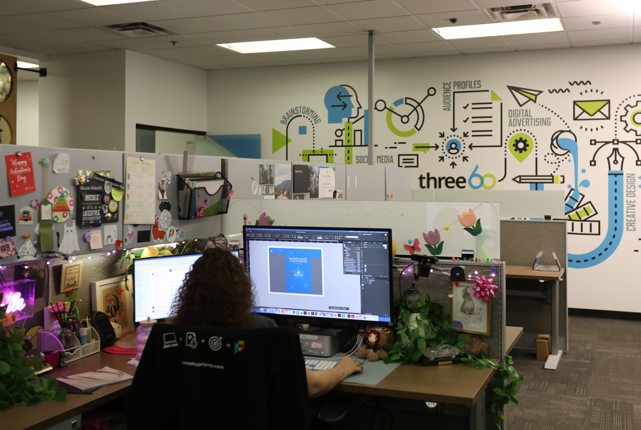 Girl working on computer at desk with creative workflow mural in the background