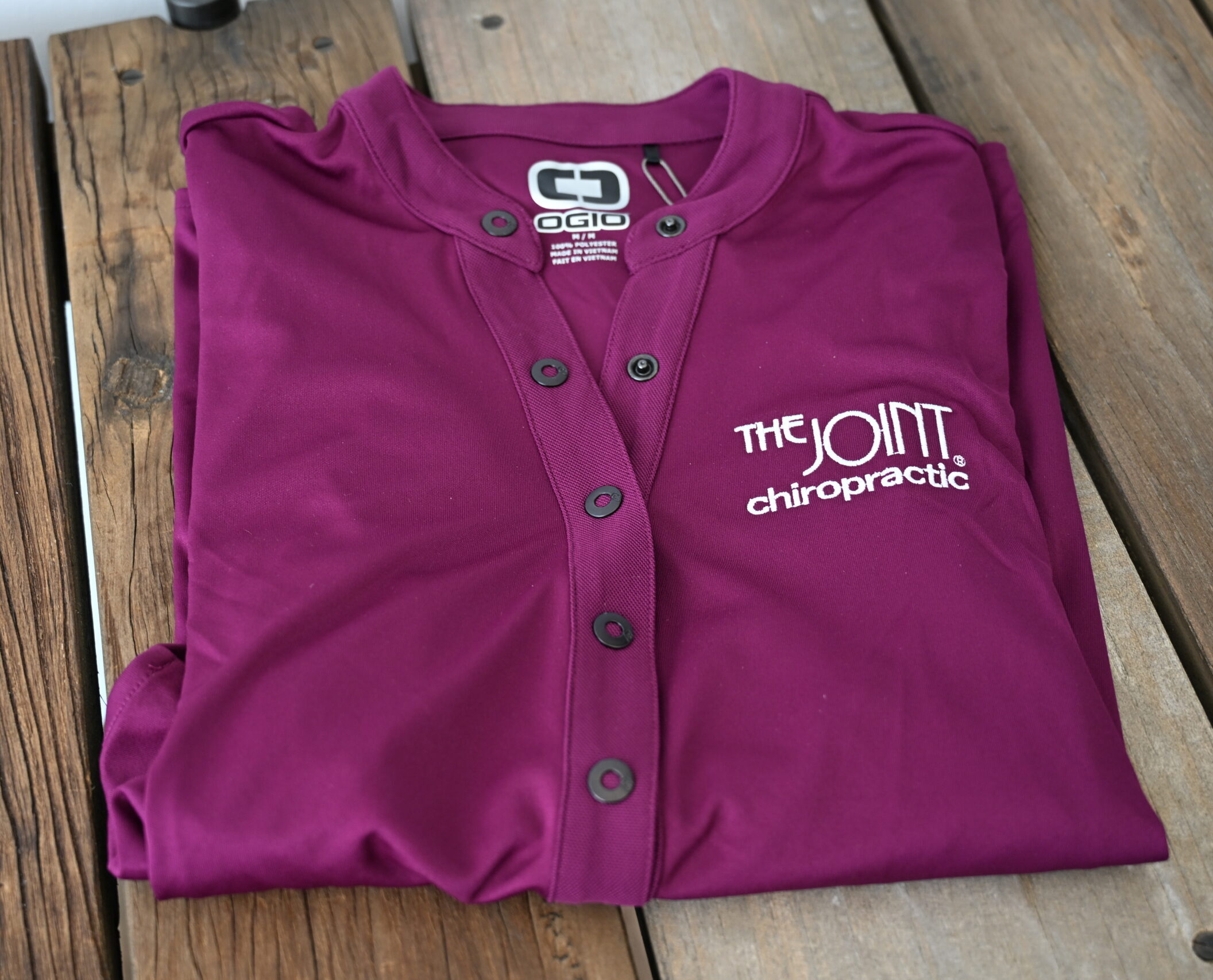 The Joint purple polo folded on a table