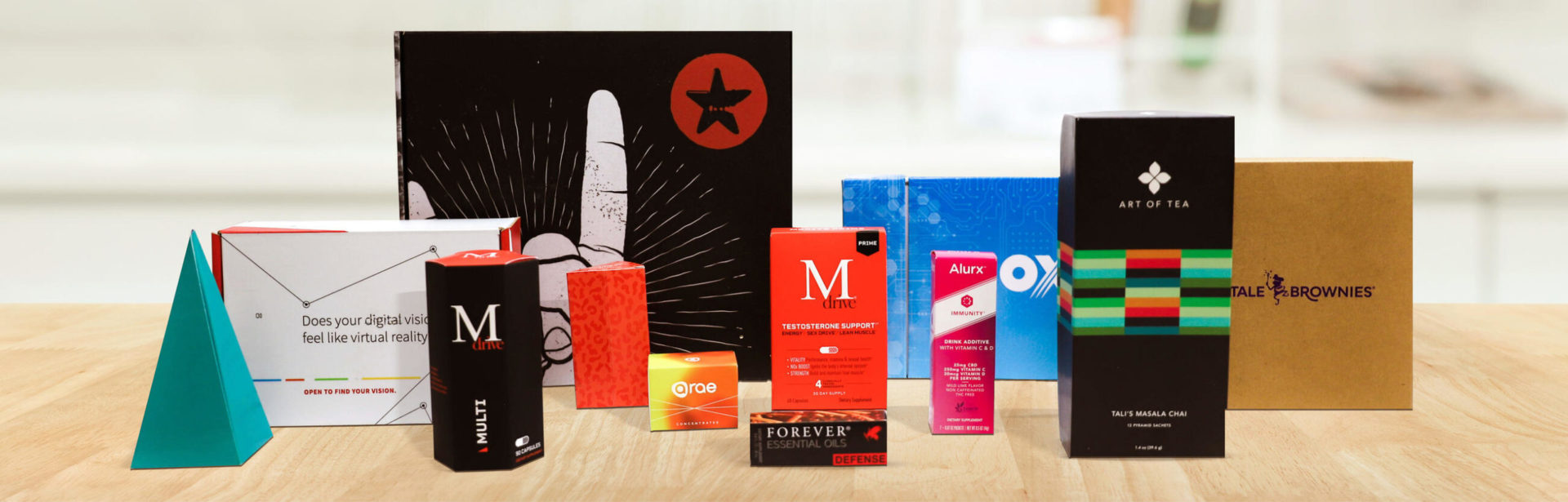 Collection of custom-branded boxes, tins, and packaging in various colors and shapes on a wood surface.