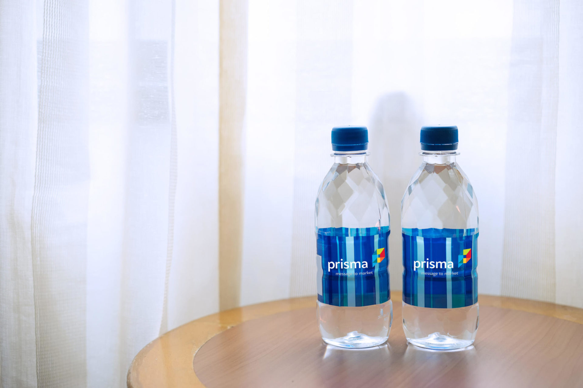 Two Prisma-branded water bottles displayed on a hotel room table.