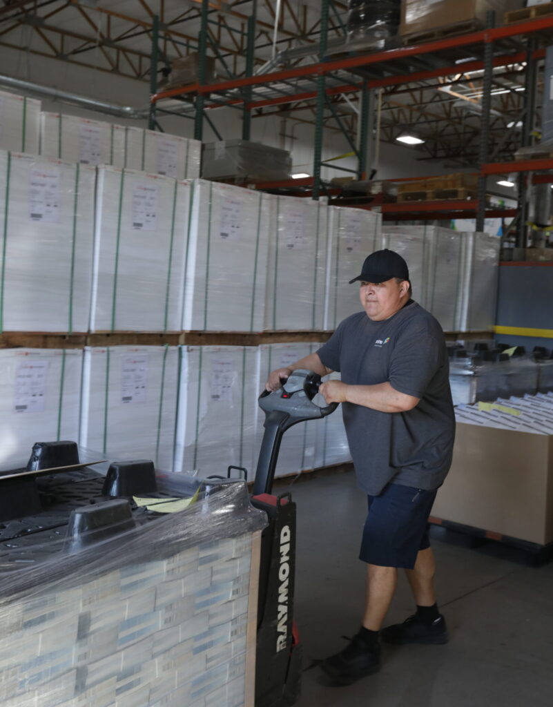 male worker moving skid of papers