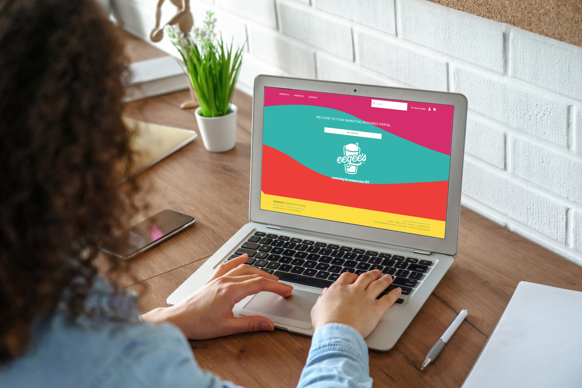 Woman typing on a laptop displaying a colorful branded online storefront.