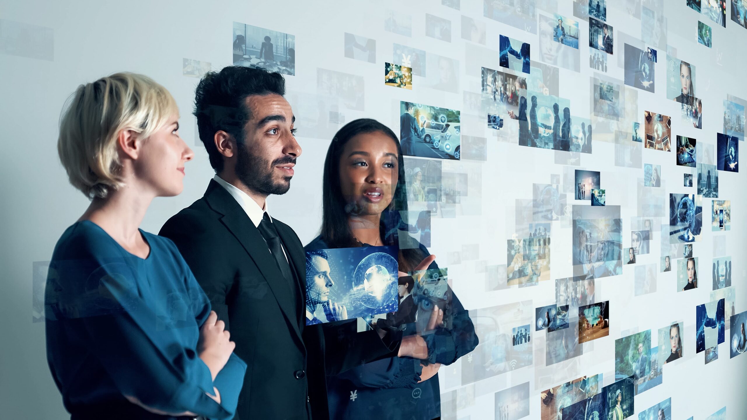 Three business professionals viewing a digital wall of data and images, symbolizing analytics.