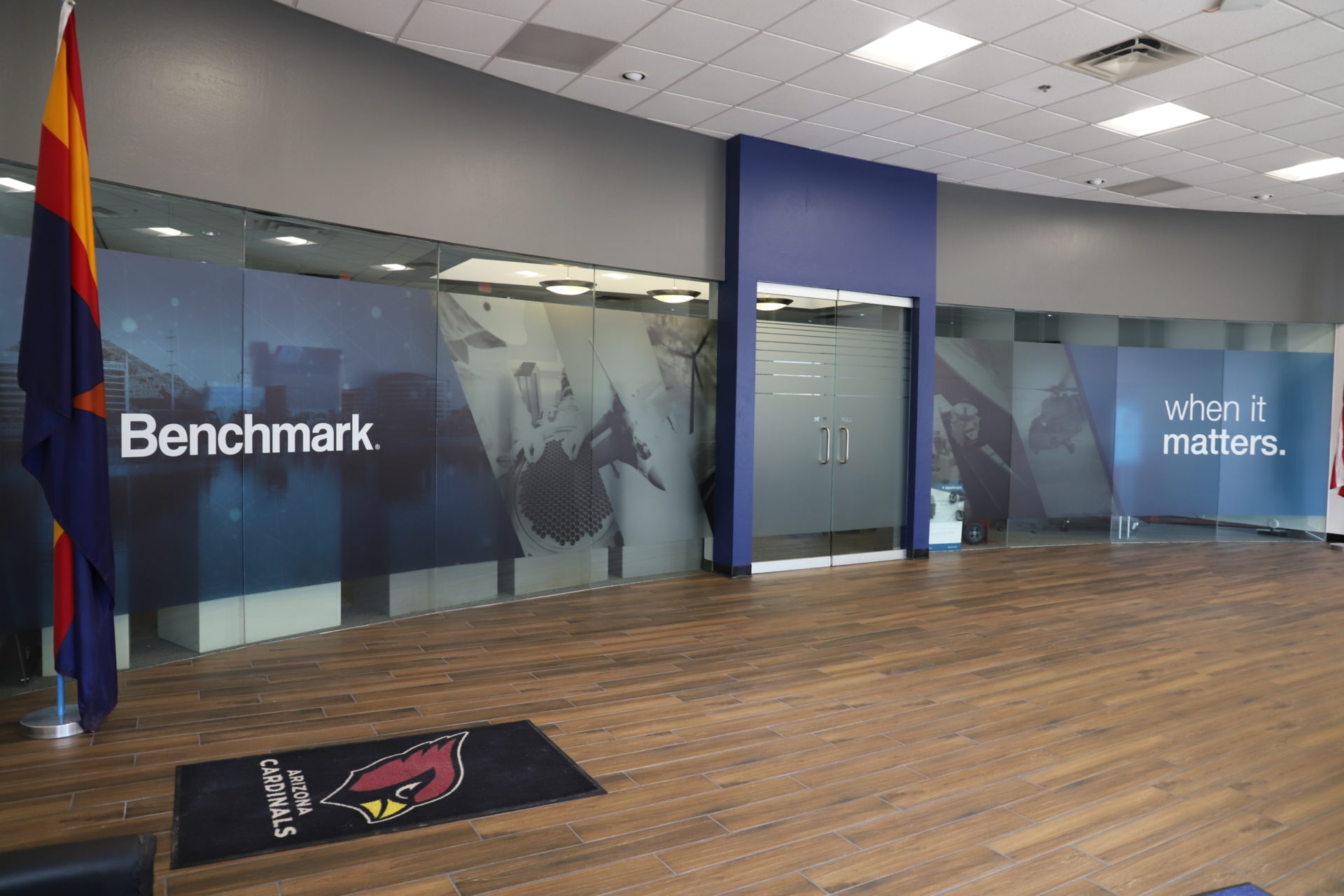 Frosted glass wall mural reading "Benchmark, when it matters" in a modern conference room.