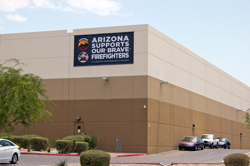 Large tribute banner honoring fallen firefighters mounted on Prisma's building exterior.
