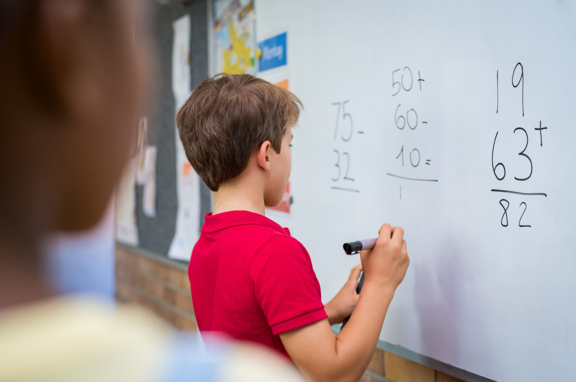 child writing math on whiteboard