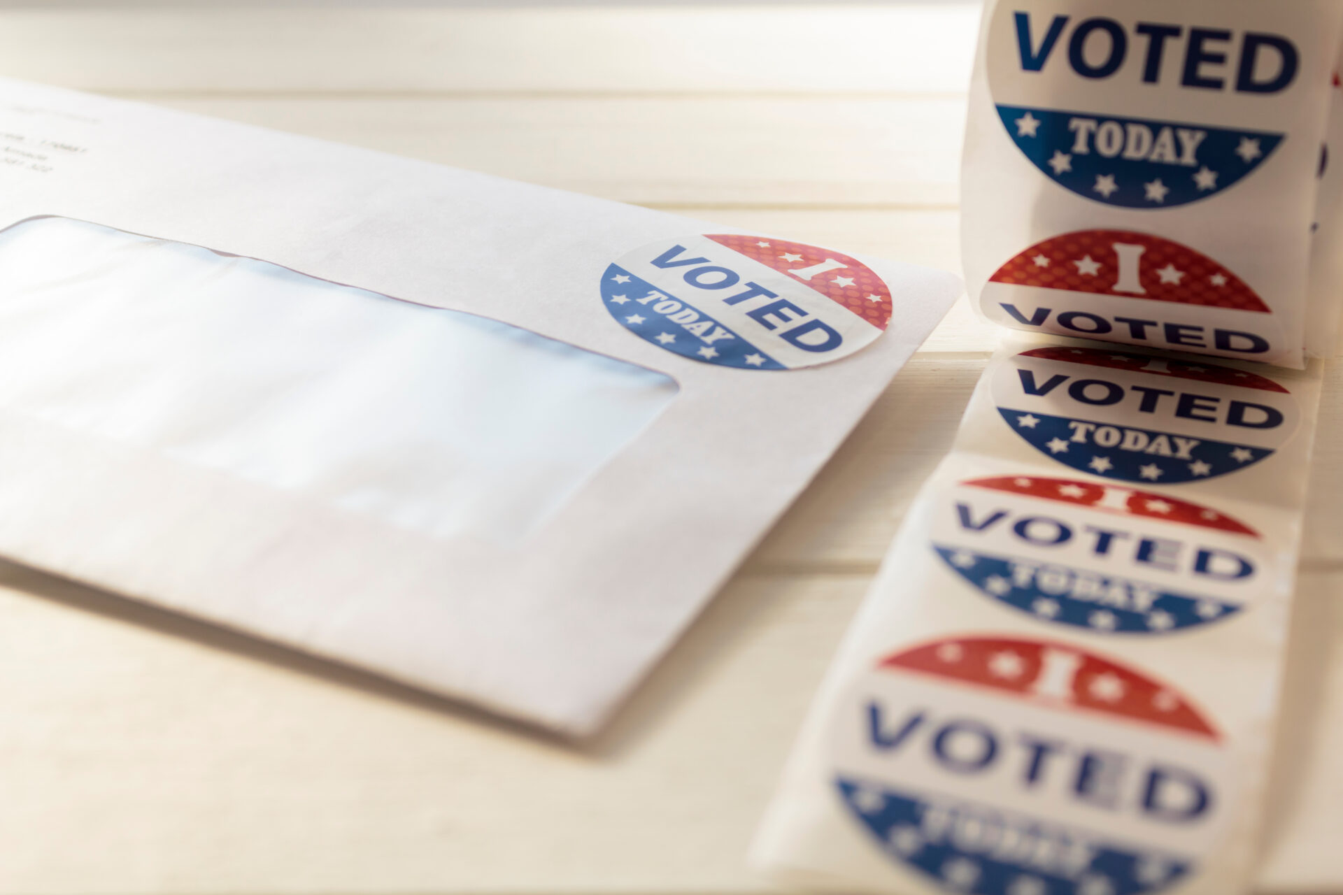 Mail-in ballot envelope next to a roll of "I Voted Today" stickers.