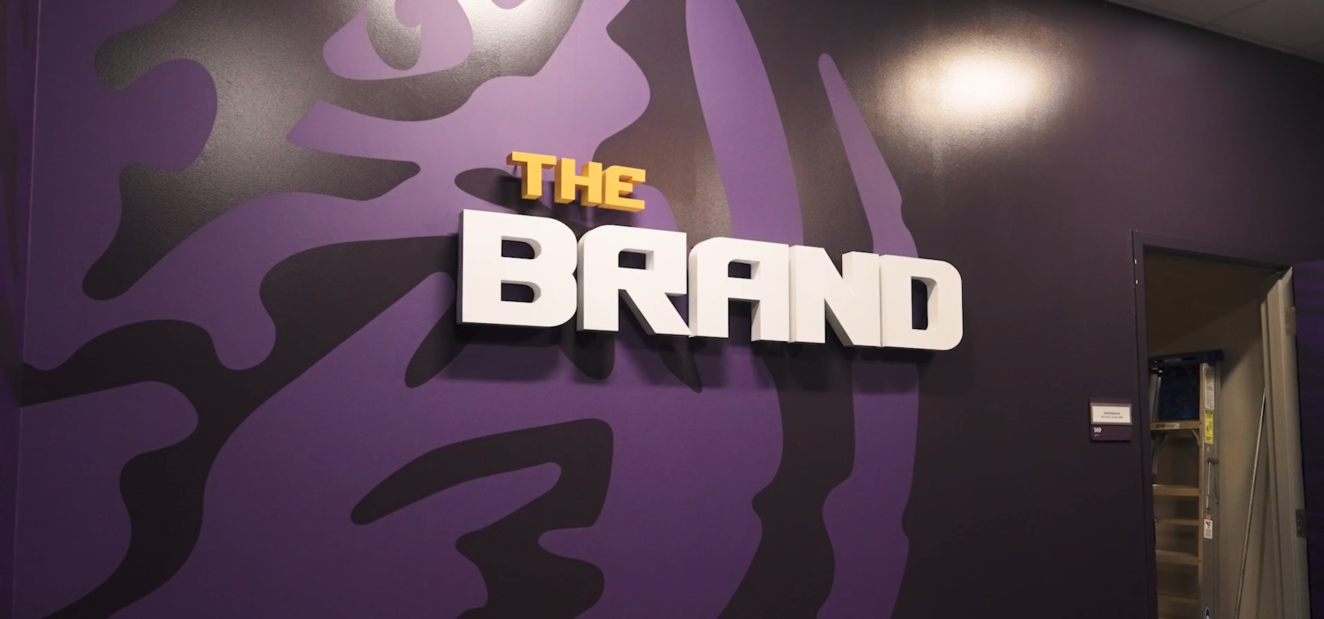 Dimensional "The Brand" lettering mounted on a purple tiger-pattern wall at LSU.