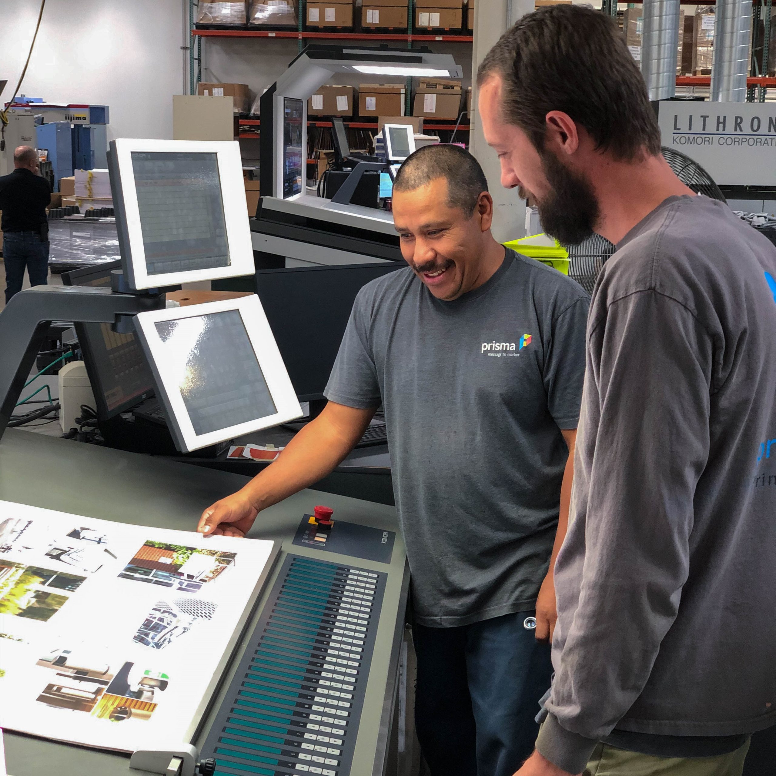 Employee's working on the printer looking at printed pieces
