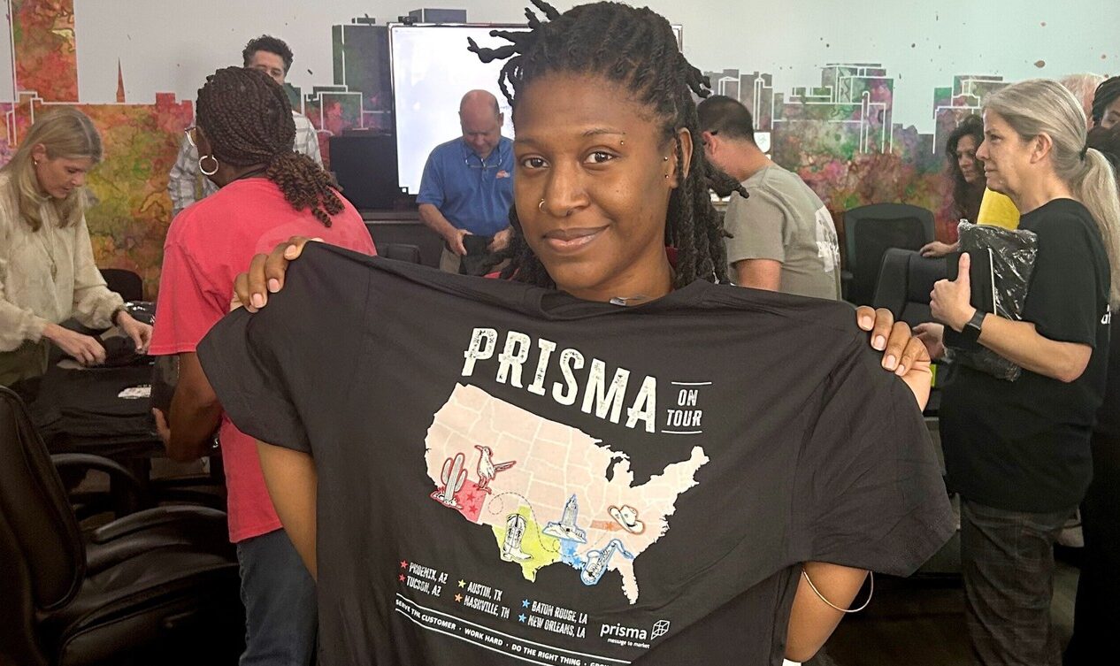 Woman holding up Prisma Townhall Tshirt